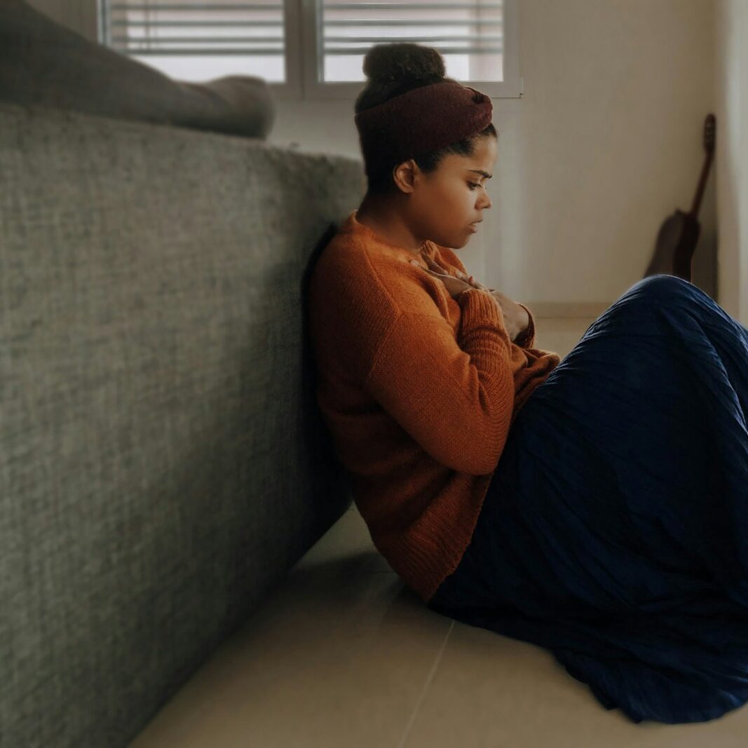 man in orange long sleeve shirt sitting on gray couch